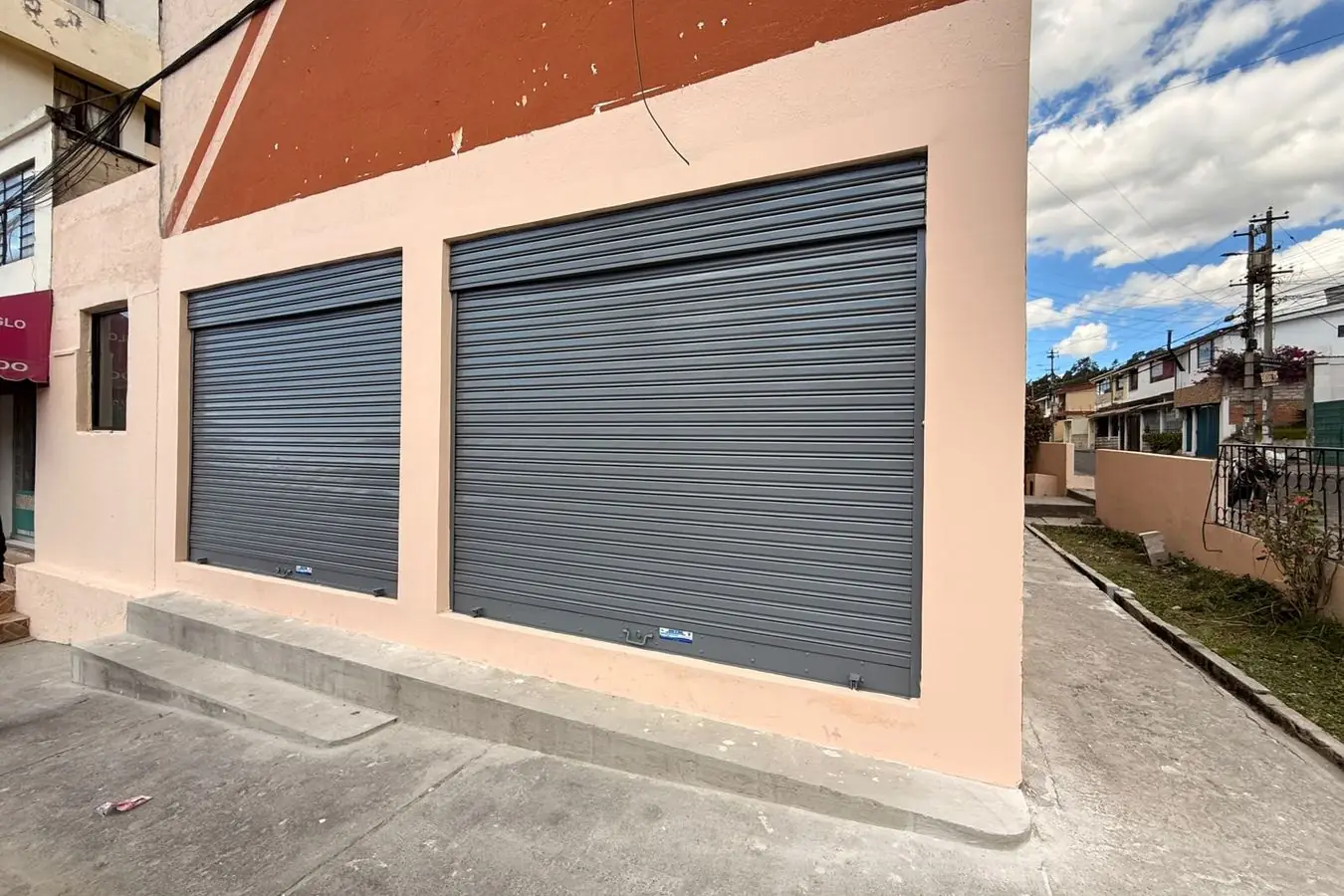 Fachada con los dos locales comerciales entregados en San Carlos, Quito, con puertas enrollables nuevas