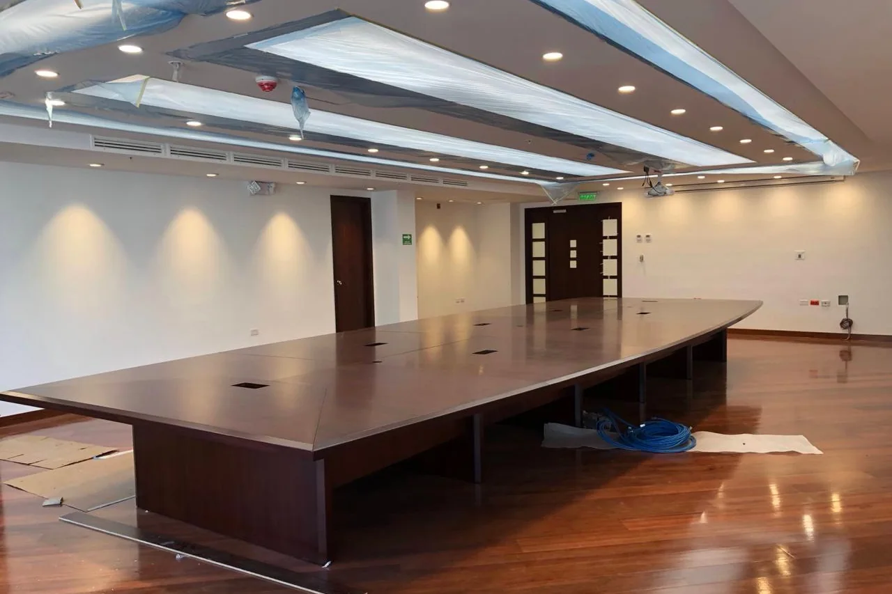 Sala de sesiones rehabilitada con piso de chanul, mesa de directorio y cielo raso con iluminación