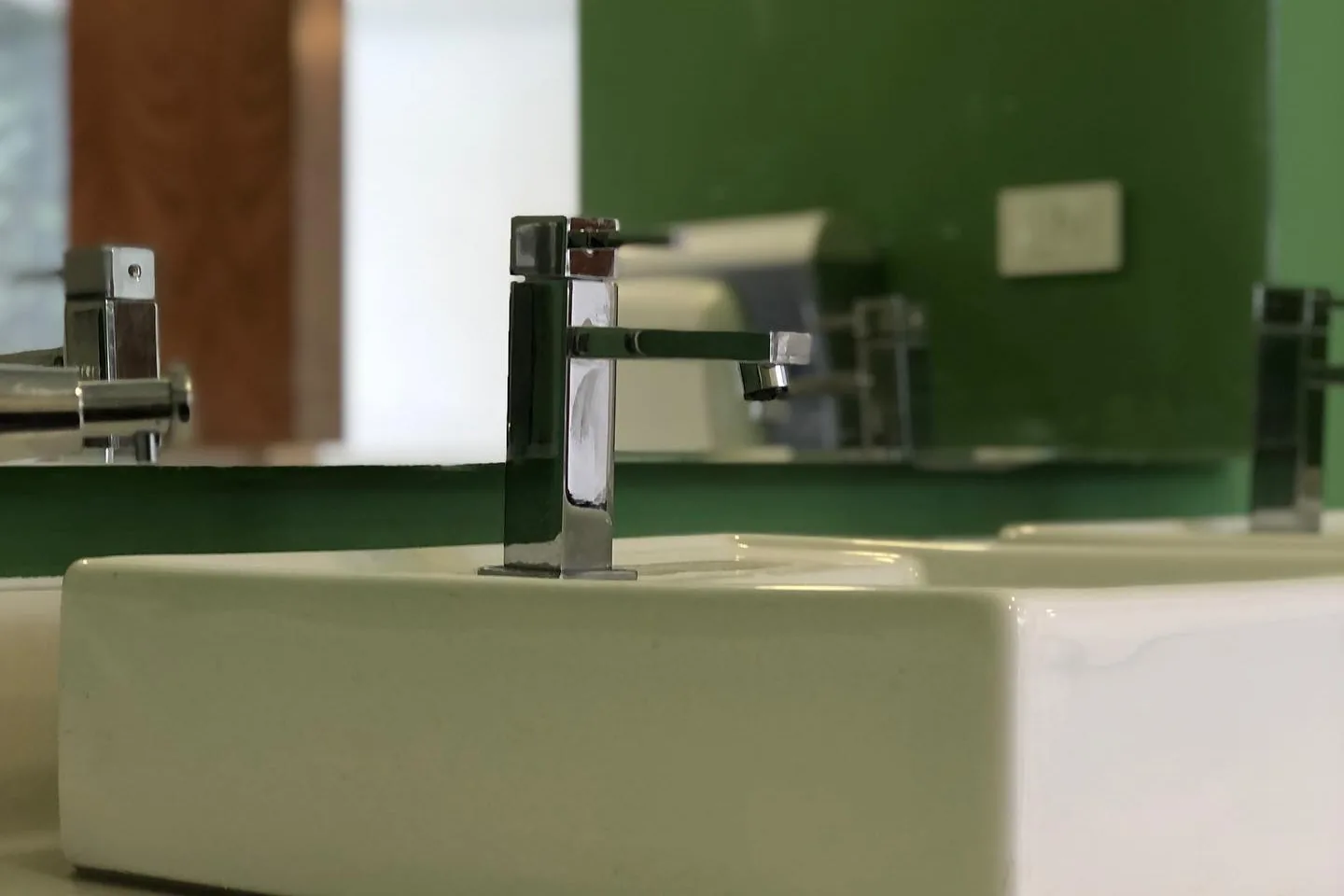 Detalle de lavabo y grifería con pared verde en el Club de Tenis Buena Vista