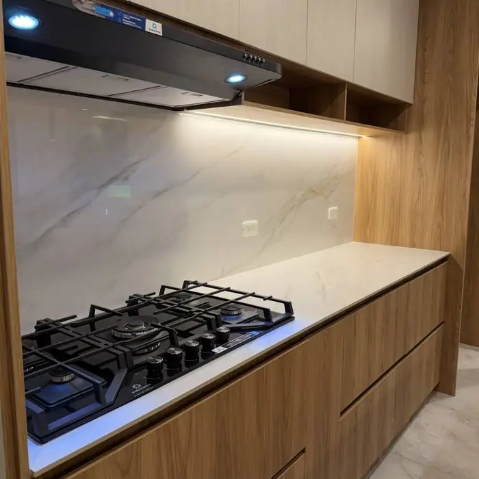Detalle de encimera a gas, mesón y salpicadero con luz bajo los muebles altos