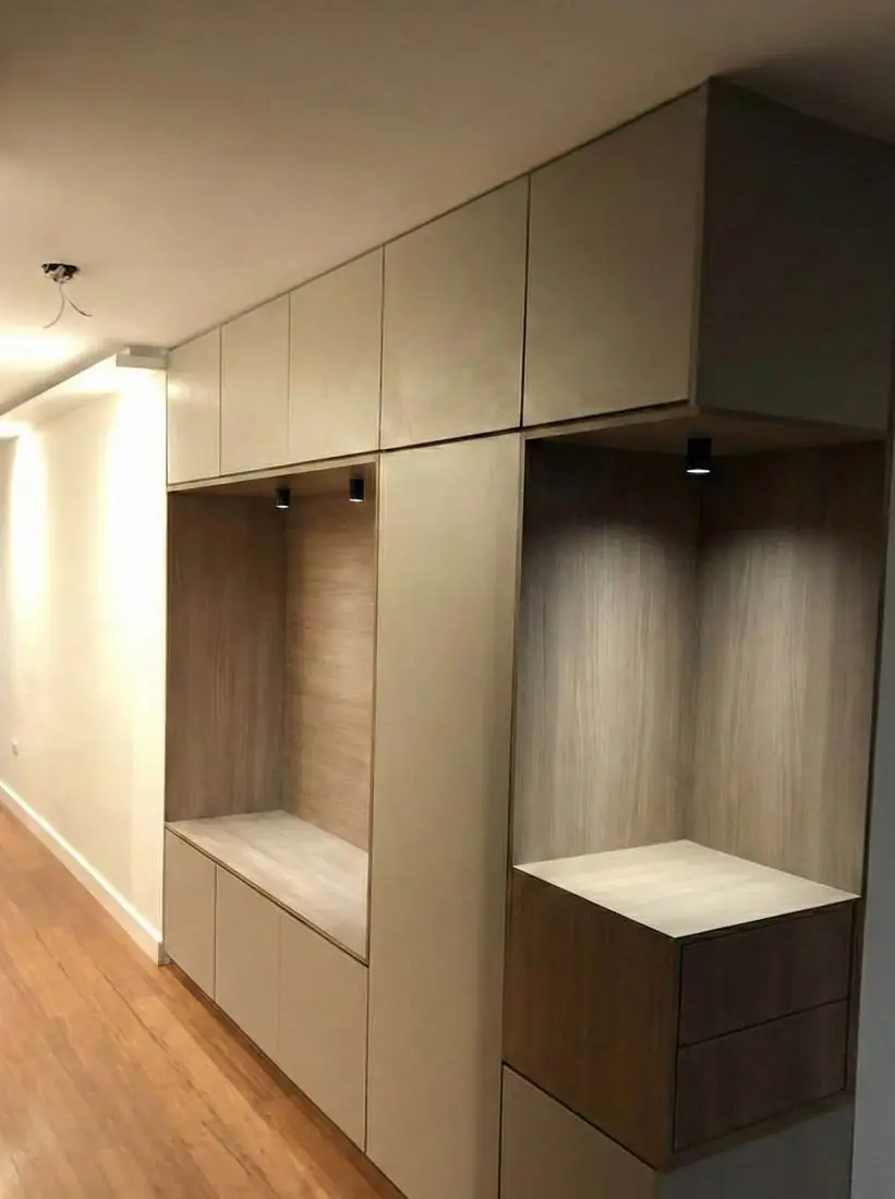 Mueble de pasillo gris con nichos de madera iluminados y cajones