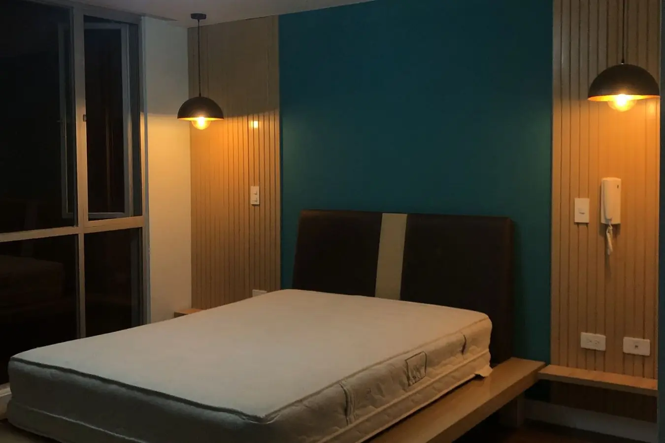 Dormitorio terminado con pared turquesa, paneles de listones y lámparas colgantes